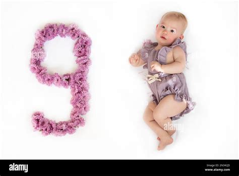 Little newborn baby girl in a purple romper. 9-month-old baby. Nine months baby milestone Stock ...