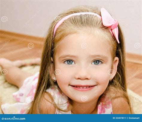 La Petite Fille De Sourire Se Trouve Sur Un Plancher De Maison Image