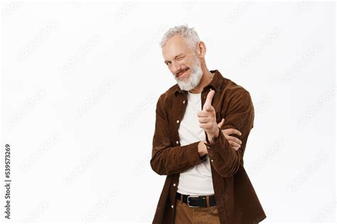 Cheerful Mature Man With Grey Hair And Beard Pointing Finger At Camera And Winking At You