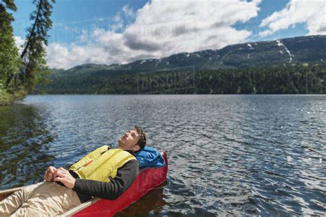 Man Reclined In Canoe And Resting In The Sunshine On Byers Lake With