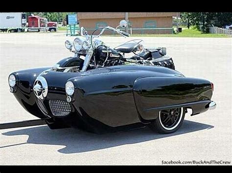 An Old Fashioned Black Car Parked In A Parking Lot Next To A Motorcycle