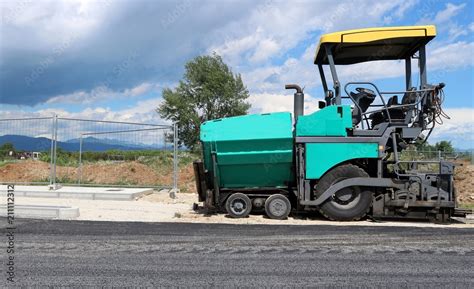 Asphalt Paver Vehicle On The Edge Of A Newly Paved Road In A New Urban