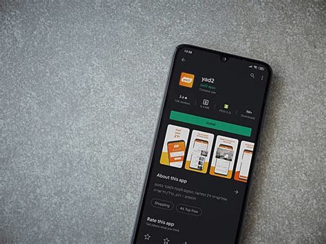 هاتف ذكي أسود يعرض تطبيق Yad2 على صفحة متجر Play صورة الخلفية والصورة