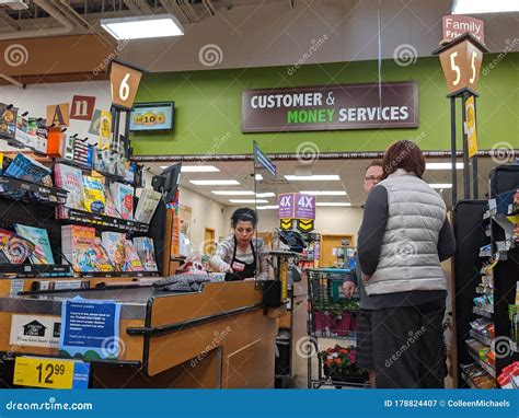 Cashier Behind A Plexiglass Wall At A Checkout Counter Inside A Fred