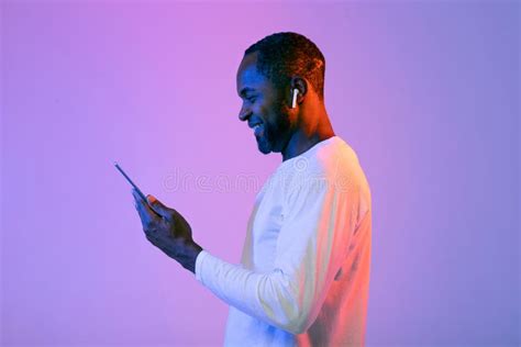 Side View Of Happy Black Man Using Earbuds And Smartphone Stock Photo