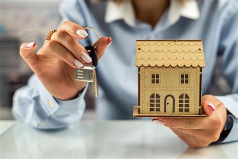 Detalhe da mão de um homem protegendo uma casa em miniatura sobre uma