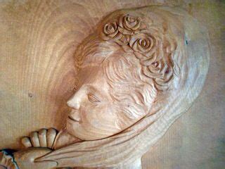 A Carving Of A Woman S Head With Flowers In Her Hair And Hands Resting