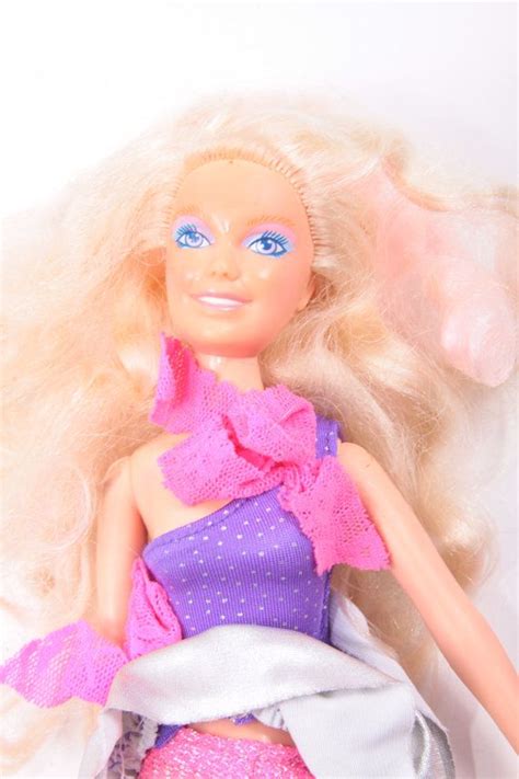 A Barbie Doll With Blonde Hair And Blue Eyes Wearing A Purple Dress On