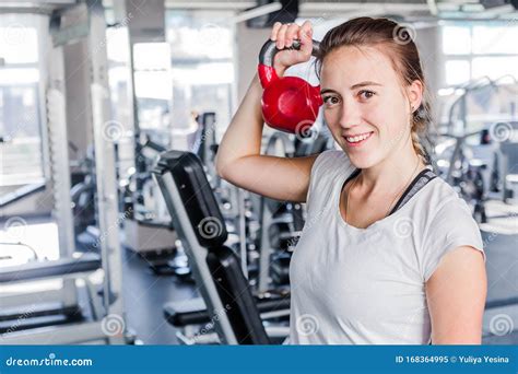 Fit Brunette Lifting Pink Kettlebell Smiling At Camera At The Gym Stock