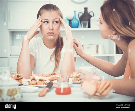 Female Talking With Young Sad Friend At The Table With Cake At Home