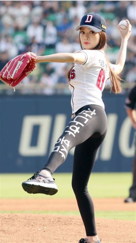 A Woman Pitching A Ball On Top Of A Baseball Field In Front Of A Crowd