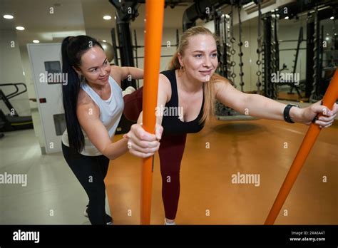 Brunette Woman Helps Blonde Woman To Perform Exercises With Gymnastic Sticks Stock Photo Alamy
