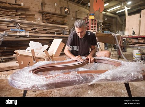 Master In The Workshop Man Polishing Wood With Sandpaper Carpentry