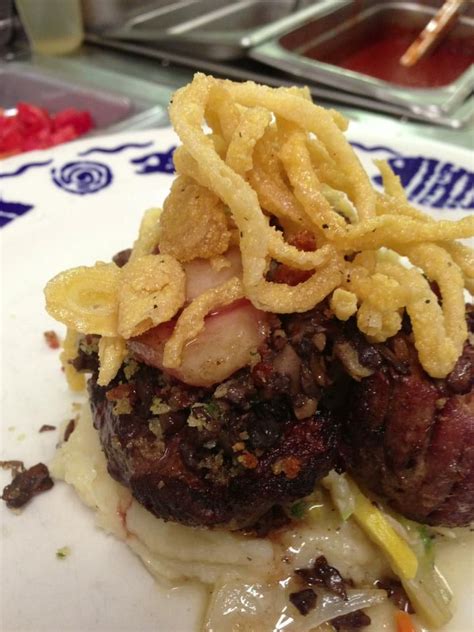 A White Plate Topped With Meat And Onion Rings