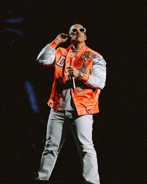 A Man In An Orange Vest And Sunglasses On Stage