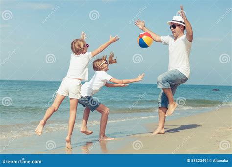 Pai E Filhas Que Jogam Na Praia No Tempo Do Por Do Sol Foto De Stock