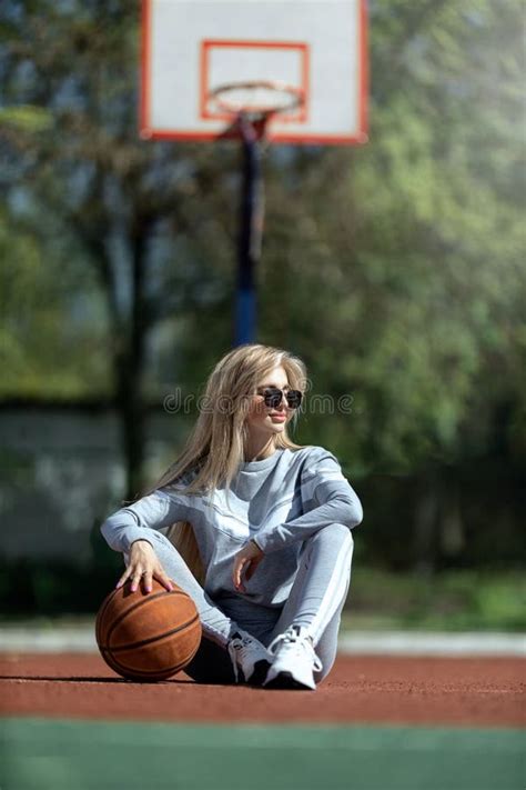 Chica Deportiva Rubia Sentada En La Cancha De Baloncesto Imagen De