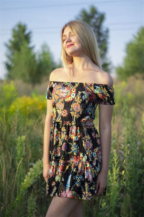 Overlight Bright Portrait Of A Charming Attractive Blonde In Flowery Dress In The Field Stock