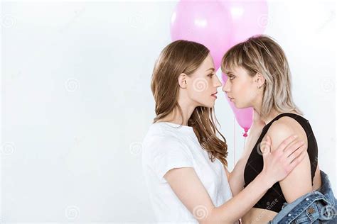 Beautiful Young Lesbian Couple Holding Pink Balloons And Looking At