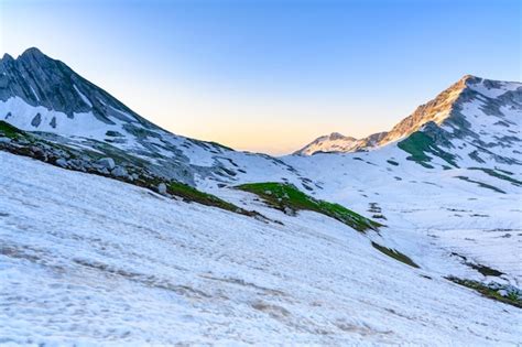 Premium Photo The Snowdrifts And Green Grass On Top Of Mountains In