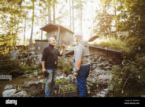 Gay Men Talking While Holding Gardening Tools At Field Stock Photo Alamy