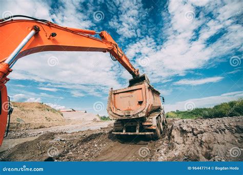 Working Excavator On Site Loading Dumper Truck During Earthmoving