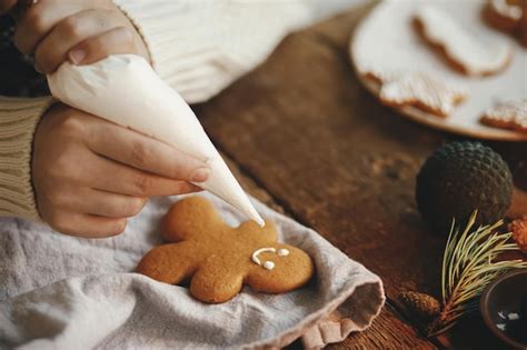 Manos decorando galletas navideñas de hombre de jengibre con glaseado