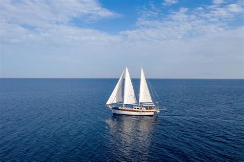 Premium Photo Sailing Boat With White Sails In The Open Sea Cloudy