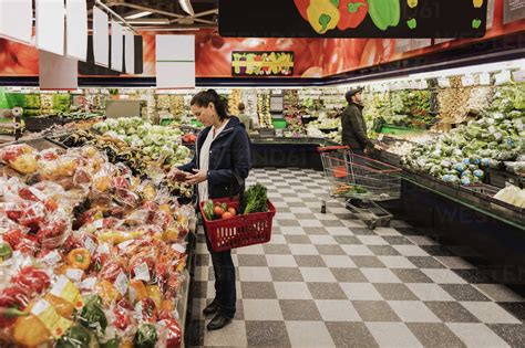 People Buying Groceries While Standing In Supermarket Stock Photo