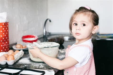 Uma Menina Bonito Pequena Que Prepara A Massa Na Cozinha Em Casa Imagem