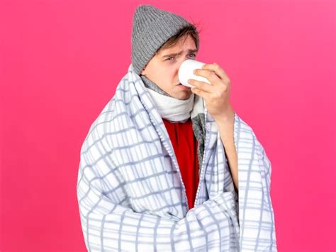 Frunciendo el ceño joven guapo rubio enfermo vestido con gorro de