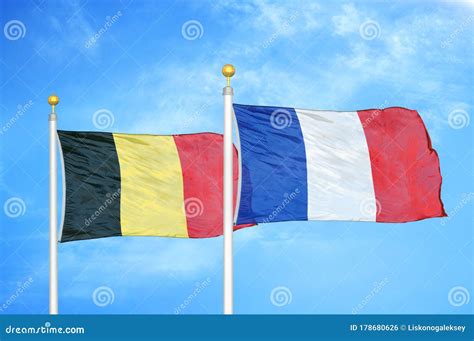 Belgium And France Two Flags On Flagpoles And Blue Cloudy Sky Stock