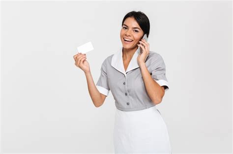 Governanta feminina jovem bonita falando no telefone celular em pé e