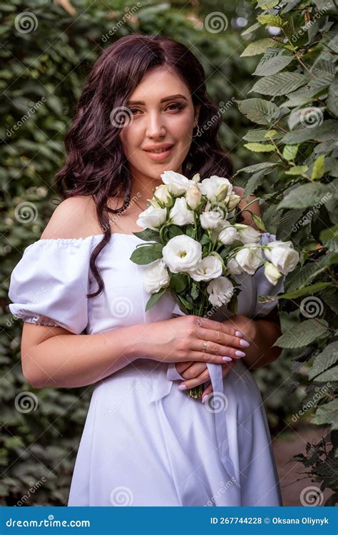 Long Haired Model With Bouquet Of White Flowers Smiles Affably Brunette Has Bared Her Shoulders