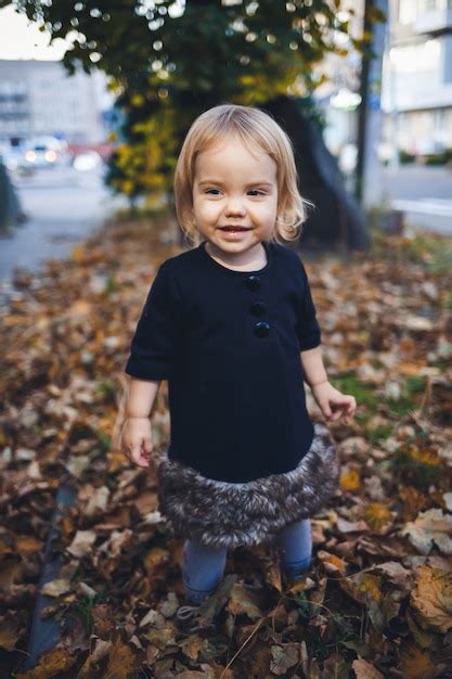 Uma Menina De Anos Est De P E Sorrindo A Crian A Joga Folhas