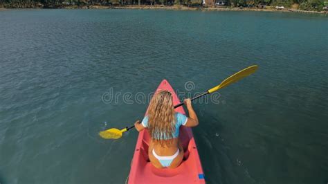 Seductive Blonde Woman In Blue Swimsuit Sails On Pink Plastic Kayak