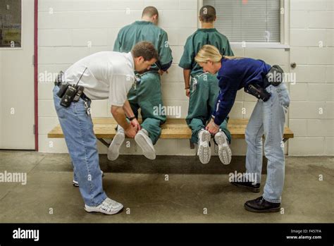 Male And Female Corrections Officers Place Leg Irons On Two Teenage