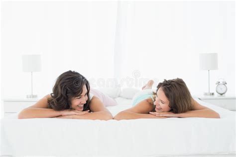 Amigos Femeninos Jovenes Sonrientes Que Mienten En Cama Foto De Archivo