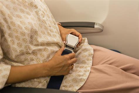 Woman Fastens Seat Belt While Sitting In A Passenger Airplane Chair By The Window 11654436