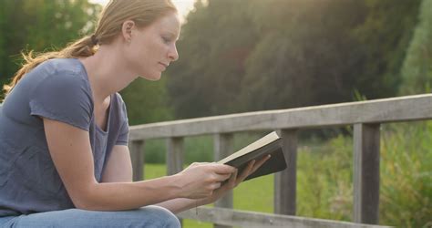 A Young Christian Woman Reading The Bible And Praying In A Park Stock