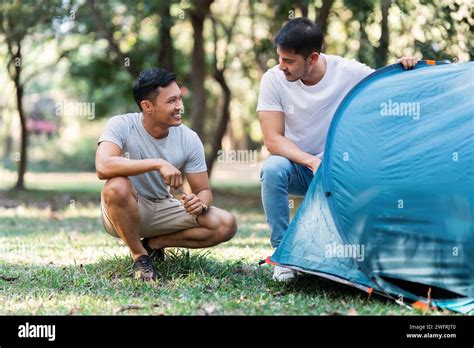Lgbtqia Gay Couple Camping Together In Woods For Holidays And Relax On Guitar Together Stock