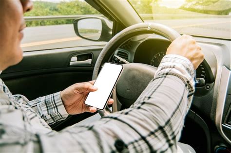 Hombre usando su teléfono mientras maneja persona sosteniendo el