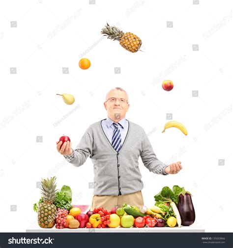 Smiling Mature Man Juggling Fruits Behind Stock Photo