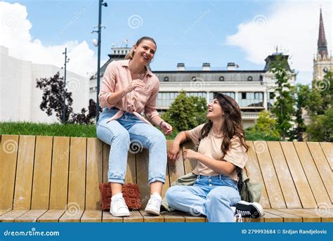 Two Best Friends Talking Outside Sitting On A Bench In A Park Women