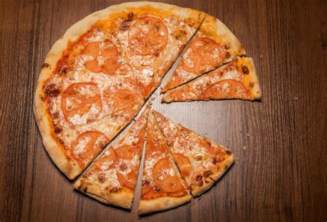 Top View Of Sliced On Pieces Pizza With Tomato Slices Stock Photo