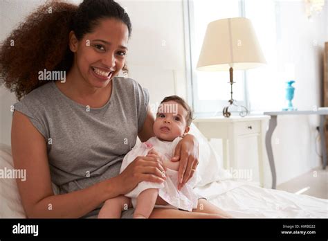 Mother Cuddling Baby Daughter In Bedroom At Home Stock Photo Alamy