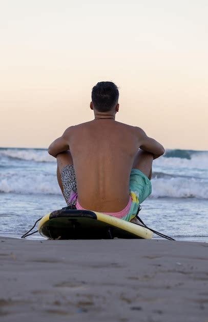 Premium Photo Surfer Sitting On The Surfboard On The Seashore