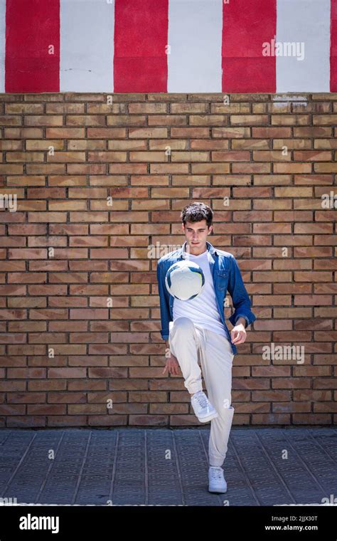 Full Length Of Young Man Looking At Football In Mid Air While Standing