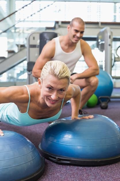 Premium Photo Trainer Assisting Woman With Push Ups At Gym