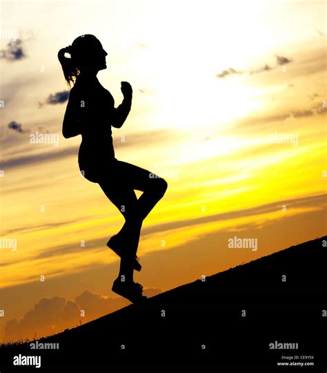 Silhouette Of A Beautiful Woman Running Up The Hill Against Yellow Sky